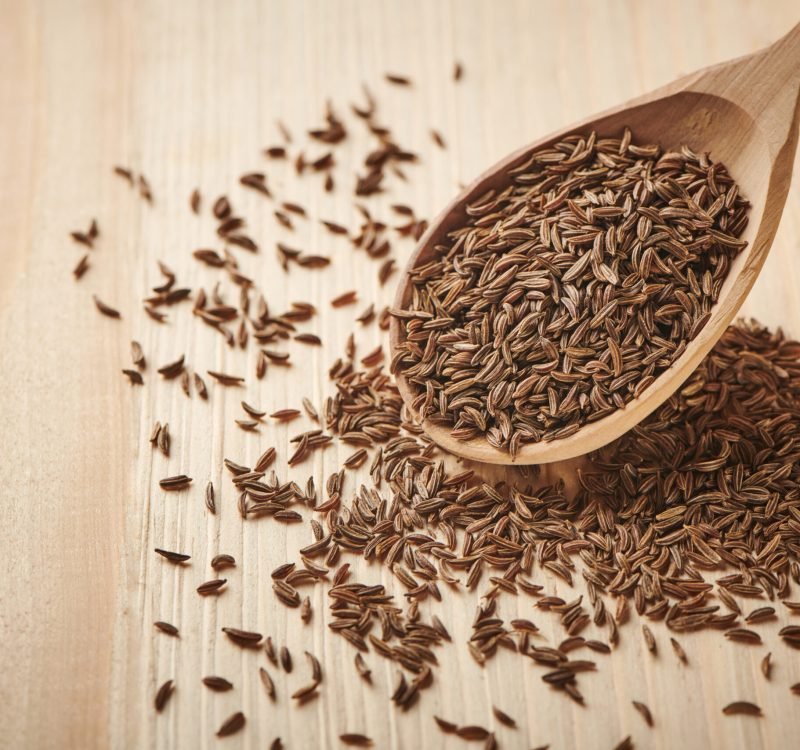Close up caraway seeds. Dried caraway seeds in wooden spoon on the table. Pile of cumin seeds. Seasoning for food cooking of worldwide kitchen. Top close up view. Close up caraway seeds. Dried caraway seeds in wooden spoon on the table. Pile of cumin seeds. Seasoning for food cooking of worldwide kitchen. Top close up view.